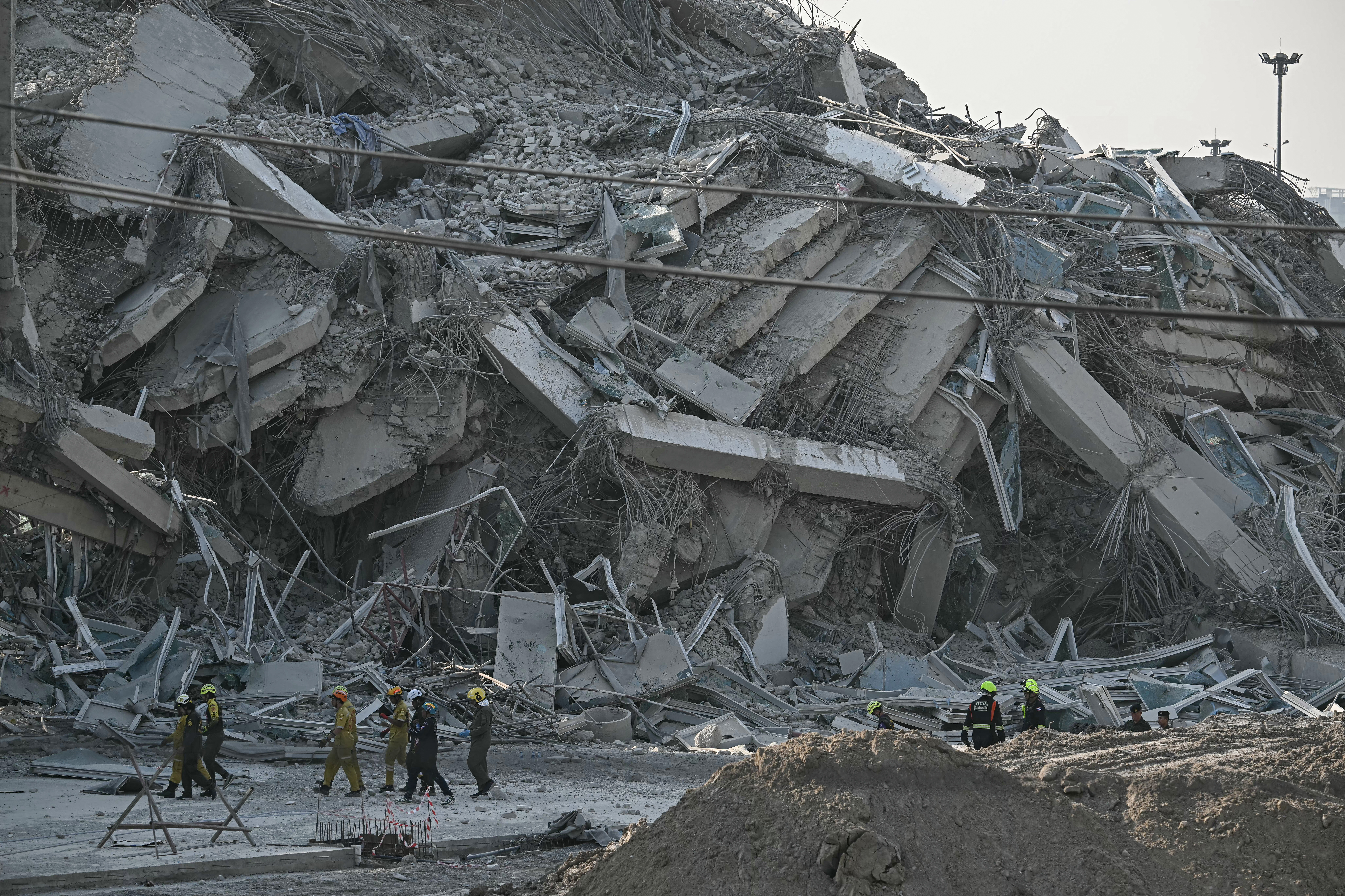PHOTO: Rescuers walk past debris of collapses building in Myanman FOR STORY: Scientists explain why Myanmar quake was so deadly