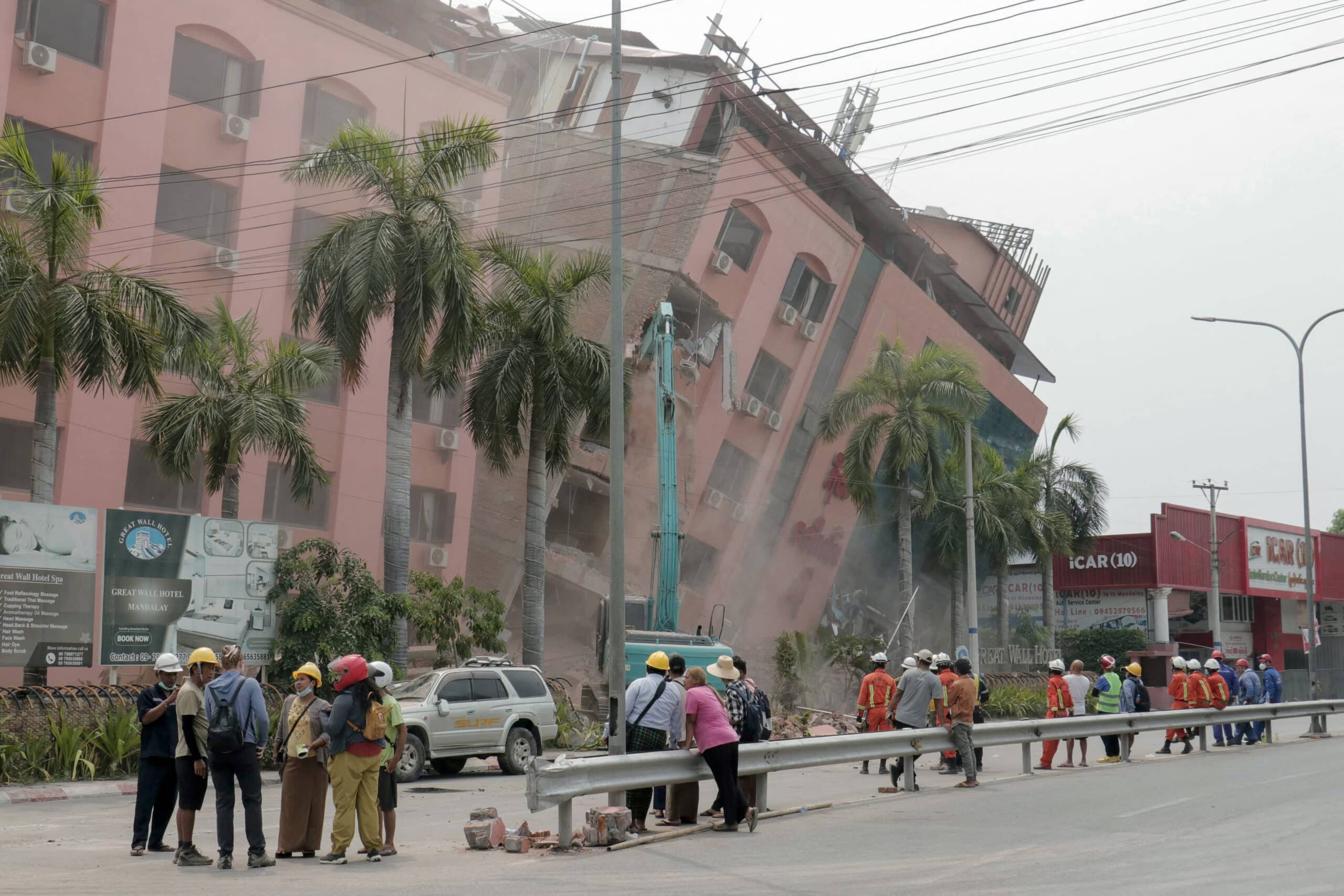 Rescue workers stand on the street next to a collapsed building in Mandalay on April 5, 2025, following the March 28 earthquake. The shallow 7.7-magnitude earthquake on March 28 flattened buildings across Myanmar, killing more than 3,000 people and making thousands more homeless. (Photo by Zaw Htun / AFP)
