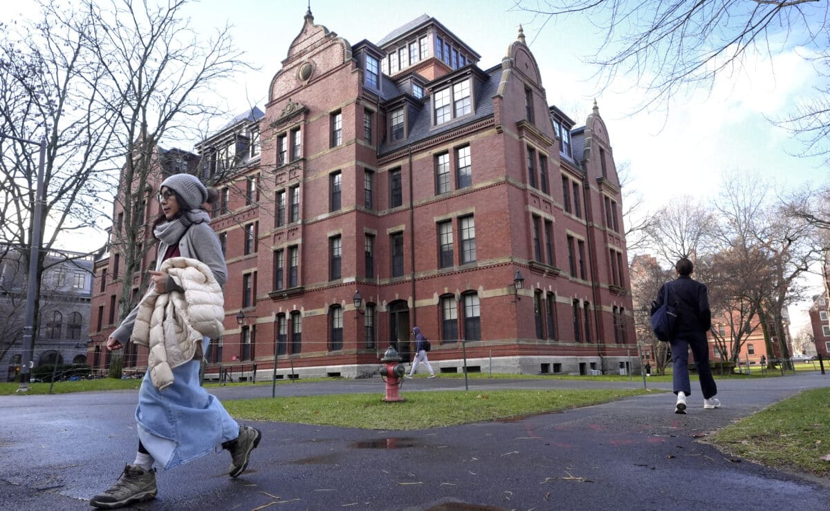 FILE - People walk between buildings, Dec. 17, 2024, on the campus of Harvard University in Cambridge, Mass. (AP Photo/Steven Senne, File)